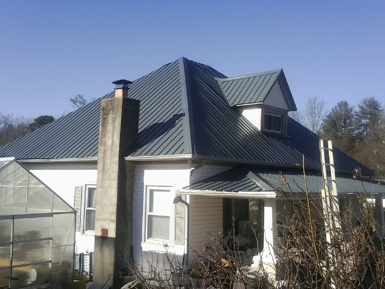 Dark blue standing seam metal roof on a white farmhouse with dormer — Slate & Tile Roof Repair by Roofing Brothers in Frenchtown