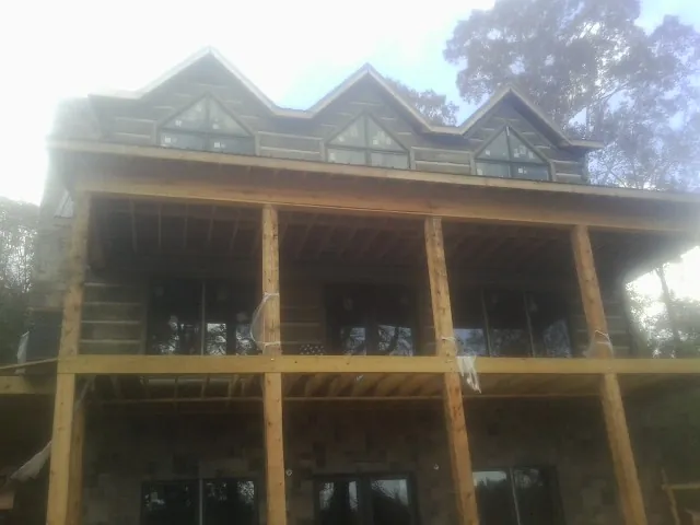 Dormers and porch framing on a large log home under construction — Roof Coating work by our crew in Frenchtown
