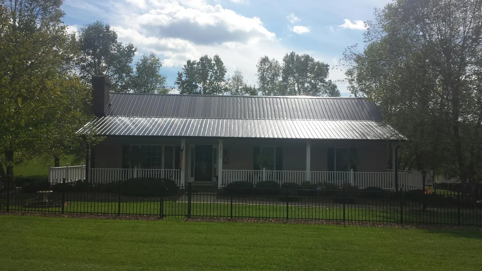 Gray metal roof on a brick ranch with a full width front porch — Gutter Guard Installation work by our crew in Frenchtown