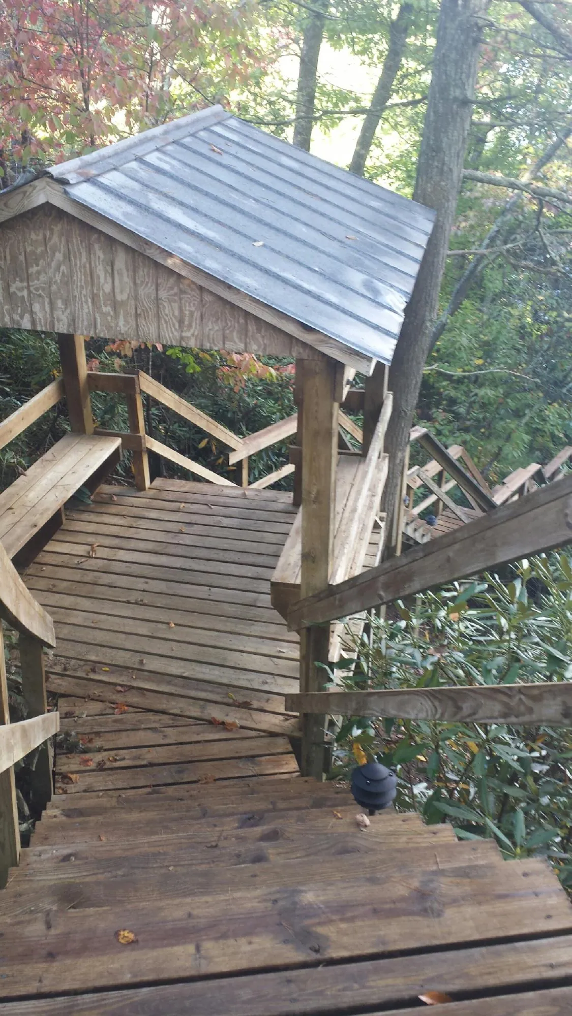 Metal roofed shelter over wooden steps on a wooded walkway — Skylight Repair & Installation work by our crew in Frenchtown