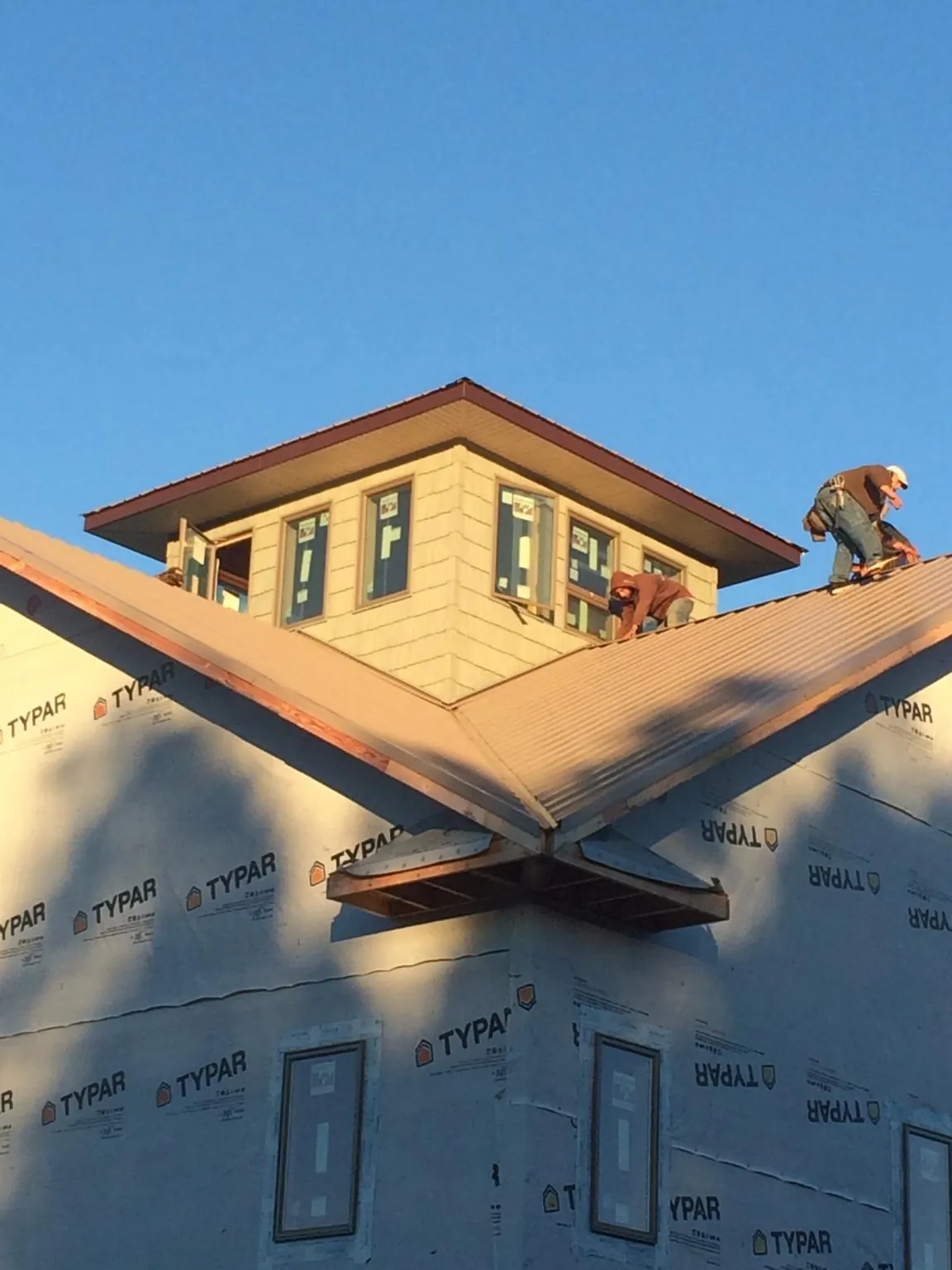 Roofers working around a rooftop cupola on a new metal roof at sunset — Roof Waterproofing in Frenchtown by Roofing Brothers